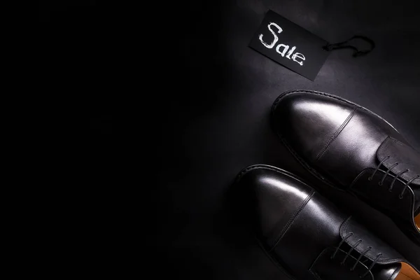 Eladó jele. Fekete oxford cipő a háttérben. Felülnézet. Másolja a hely. — Stock Fotó