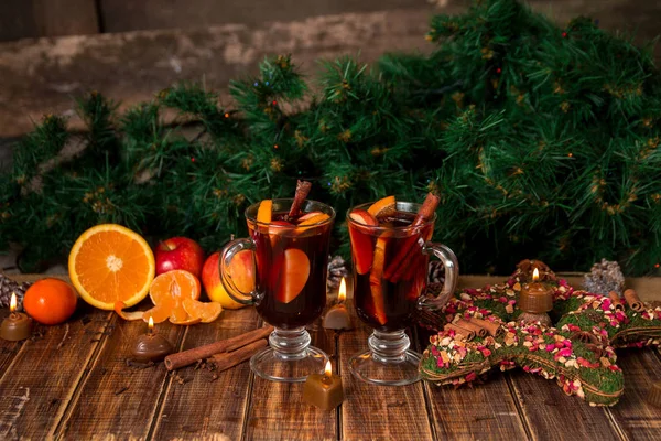 Χριστουγεννιάτικο ζεστό κρασί με φρούτα και μπαχαρικά σε ξύλινο τραπέζι. Χριστούγεννα διακοσμήσεις στο παρασκήνιο. Δύο ποτήρια. Χειμώνα του πλανήτη ποτό συνταγή συστατικά στη γύρω περιοχή. — Φωτογραφία Αρχείου