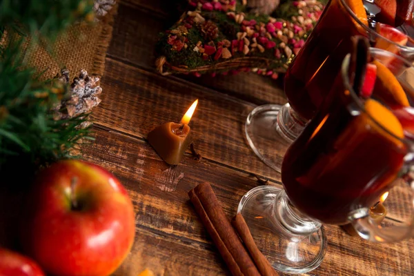 Ζεστό κρασί με φρούτα, κεριά, μπαχαρικά στο ξύλινο τραπέζι. Χριστούγεννα. Χειμώνα του πλανήτη ποτό συνταγή συστατικά γύρω. Δύο Κύπελλο, γυαλιά. — Φωτογραφία Αρχείου