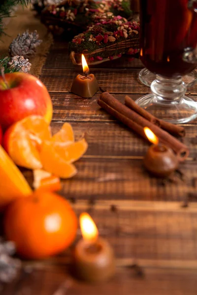 Candela, frutta all'arancia, mela, bastoncini di cannella vicino al vin brulè su sfondo di legno. Addobbi natalizi. Anno nuovo . — Foto Stock