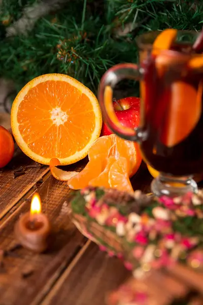 Gyertya, narancssárga gyümölcs, alma, fahéj rúd, forralt bor, fa háttér közelében. Karácsonyi dekoráció. Új év. — Stock Fotó