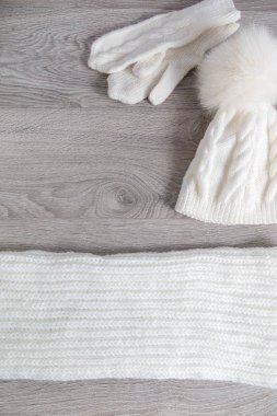 Örme soğuk hava Aksesuar tablo. Beyaz şapka, atkı karınca gri ahşap arka plan eldiven. Üstten Görünüm. Kopya alanı.
