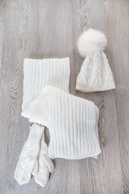 Örme soğuk hava Aksesuar tablo. Beyaz şapka, atkı karınca gri ahşap arka plan eldiven. Üstten Görünüm.