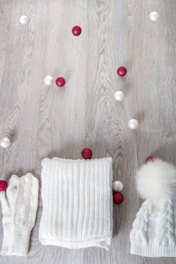 Yeni yıl ağacı topları masada yakınındaki örme soğuk hava aksesuar. Beyaz şapka, atkı karınca gri ahşap arka plan eldiven. Üstten Görünüm. Noel dekorasyonu. Kopya alanı.