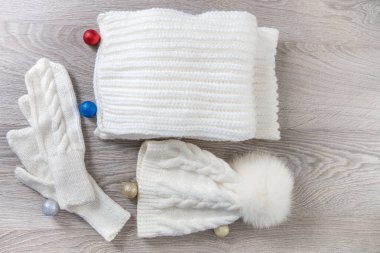Yeni yıl ağacı topları masada yakınındaki örme soğuk hava aksesuar. Beyaz şapka, atkı karınca gri ahşap arka plan eldiven. Üstten Görünüm. Noel dekorasyon.
