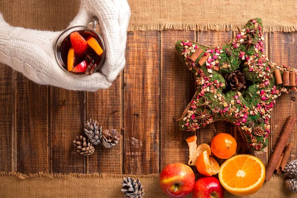 Vino rimuginato in mani di donna in guanti lavorati a maglia bianchi vicino a spezie e ingredienti di frutto su tavolo di legno. Bevanda riscaldante invernale. Natale. Anno nuovo. Vista dall'alto . — Foto Stock