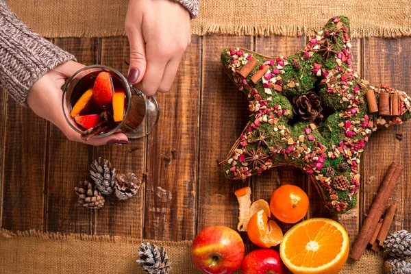 Vino rimuginato in mani femminili, spezie e ingredienti di frutta sul tavolo di legno. Bevanda riscaldante invernale. Natale. Vista dall'alto . — Foto Stock