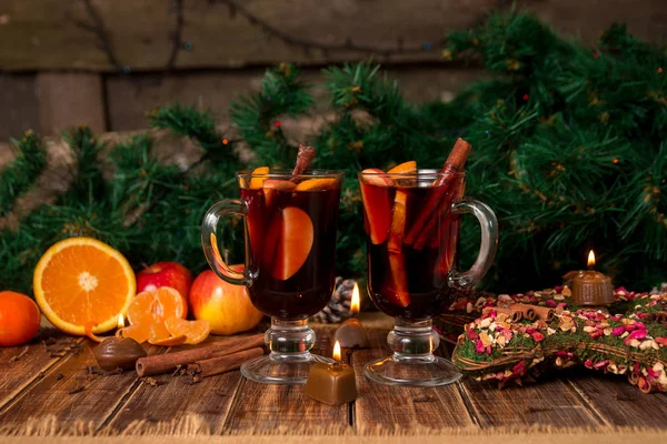 Χριστουγεννιάτικο ζεστό κρασί με φρούτα και μπαχαρικά σε ξύλινο τραπέζι. Χριστούγεννα διακοσμήσεις στο παρασκήνιο. Δύο ποτήρια. Χειμώνα του πλανήτη ποτό συνταγή συστατικά στη γύρω περιοχή. — Φωτογραφία Αρχείου