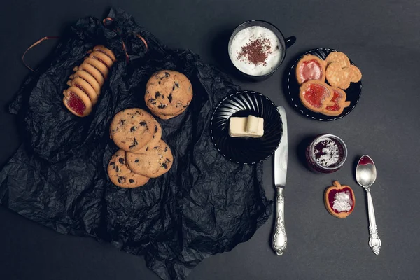 Taza de café, capuchino con galletas de chocolate y galletas sobre fondo de mesa negro. Hora del descanso de la tarde. El desayuno. Vista superior . — Foto de Stock