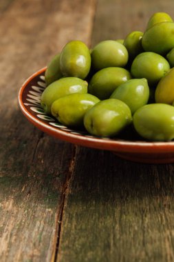 Yeşil zeytin ahşap arka plan üzerinde kahverengi kase. Yakın çekim. Kopya alanı.