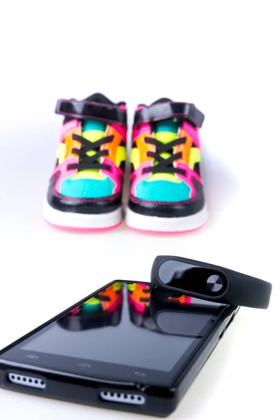 Rastreador de fitness y smartphone cerca de zapatillas multicolor. Aislado . —  Fotos de Stock