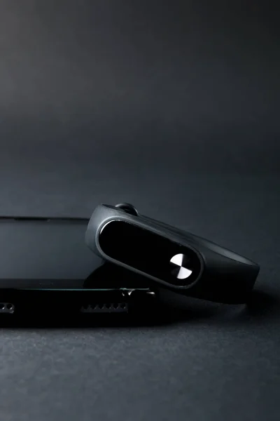Pulsera deportiva y smartphone sobre fondo negro . — Foto de Stock