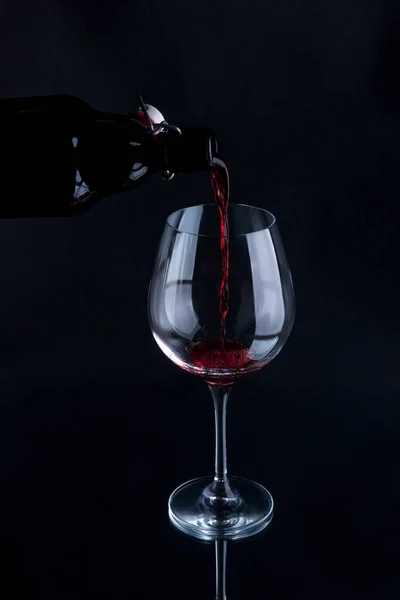 Червоне вино вливається в келих винограду. Ізольовані на чорному тлі . — стокове фото
