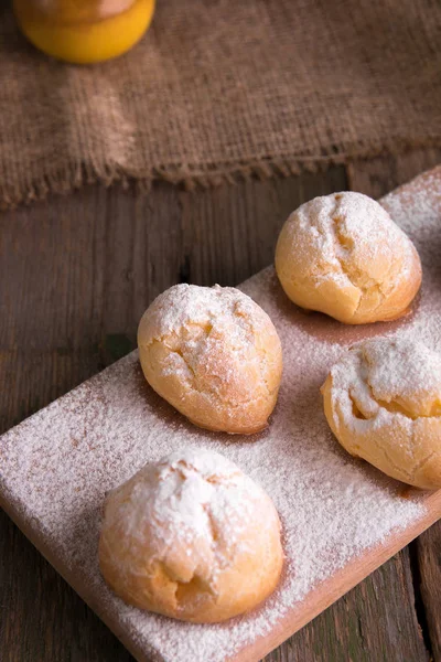 Profiteroli cu zahăr pudră pe fundal din lemn. Stilul rustic. Close up . — Fotografie, imagine de stoc