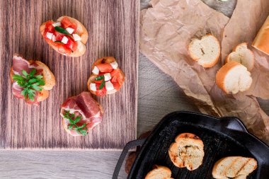 Izgara tava şerefine. Domates, roka, jambon ve mozzarella ile crostini kümesi. İtalyan yemekleri, ev yapımı bruschetta.