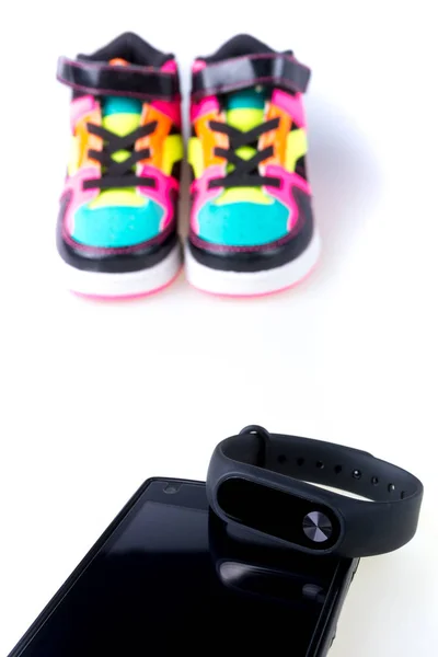 Rastreador de fitness y smartphone cerca de zapatillas multicolor. Aislado . — Foto de Stock