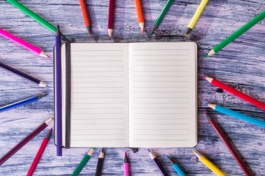 Yakınındaki Not ahşap arka plan üzerinde renkli kalemler. Üstten Görünüm. Kopya alanı.