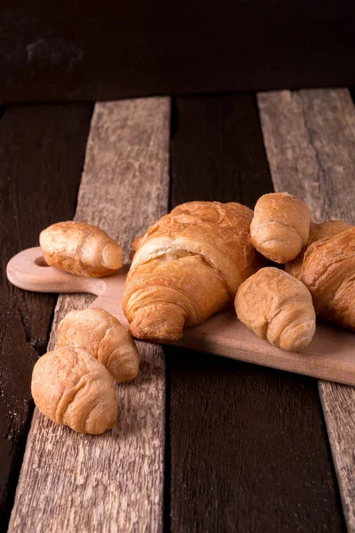 Croissants on board on wooden background. Rustic style. — Stock Photo, Image