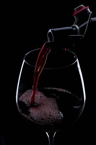 Verser le vin rouge de la bouteille dans le verre à vin — Photo