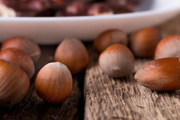 Piezas de chocolate con nueces de avellana sobre fondo de madera de plato blanco. de cerca . —  Fotos de Stock