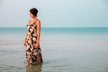 Sığ okyanus su bir çiçek elbise ayakta kadında. Deniz kızı. mesafe içine arıyorum.