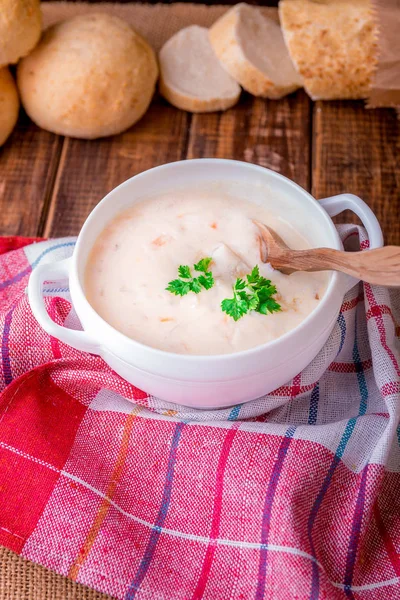 Soupe à la crème dans un bol blanc près du pain sur bois — Photo