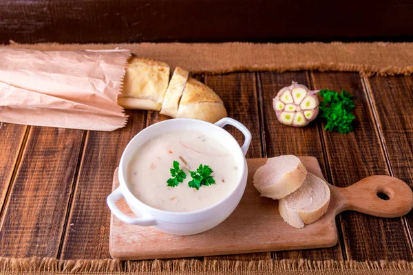 Sopa de creme em tigela branca perto de pão em madeira — Fotografia de Stock