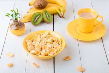 Tahıl gevreği ve beyaz zemin üzerine çiçekli vazo yakın meyve sağlıklı kahvaltı. Sarı tonu