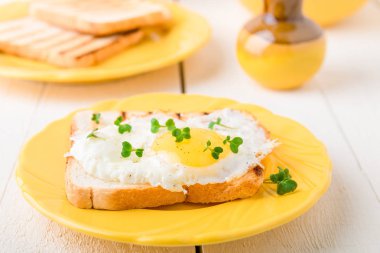 Yumurta beyaz ahşap zemin üzerine sarı plaka ile tost. Sağlıklı kahvaltı.