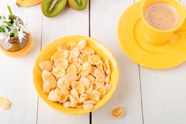 Tahıl gevreği ve beyaz zemin üzerine çiçekli vazo yakın meyve sağlıklı kahvaltı. Sarı tonu. Üstten Görünüm.