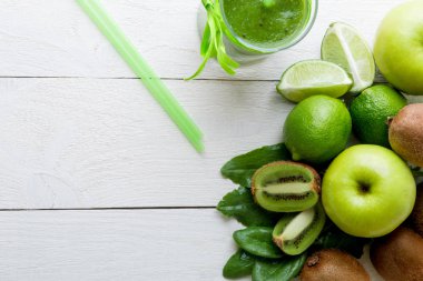 Yeşil smoothie yakınındaki beyaz ahşap zemin üzerinde bunun için malzemeler. Elma, limon, ıspanak. Detoks. Sağlıklı içecek.