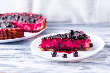 Parça ile üzümü renkli ahşap arka plan üzerinde beyaz plaka üzerinde cheesecake.