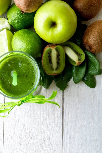 Batido verde cerca de los ingredientes para ello sobre fondo de madera blanca. Manzana, lima, espinacas. Desintoxicación. Bebida saludable. Vista superior . —  Fotos de Stock