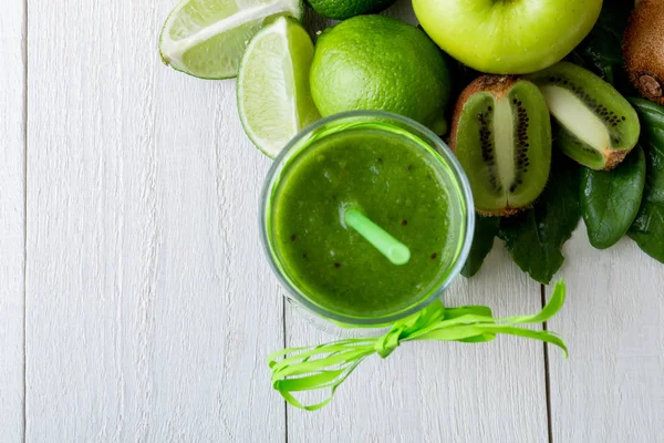 Batido verde cerca de los ingredientes para ello sobre fondo de madera blanca. Manzana, lima, espinacas. Desintoxicación. Bebida saludable. Vista superior . —  Fotos de Stock