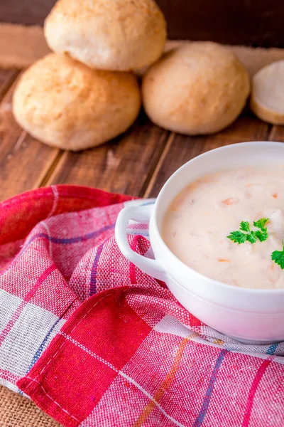 Soupe à la crème dans un bol blanc avec cuillère en bois près du pain sur fond en bois. Style rustique — Photo