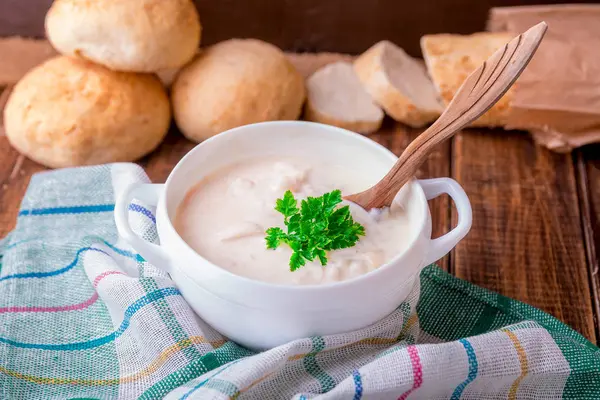 Soupe à la crème dans un bol blanc avec cuillère en bois près du pain sur fond en bois. Style rustique — Photo
