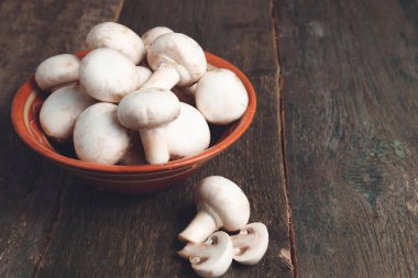 Ahşap arka plan üzerinde kahverengi kase taze beyaz mantar champignon. Üstten Görünüm. Kopya alanı.