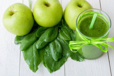 Yeşil smoothie yakınındaki beyaz ahşap zemin üzerinde bunun için malzemeler. Elma, limon, ıspanak. Detoks. Sağlıklı içecek.