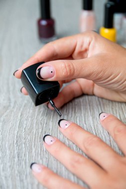 Siyah oje el ile manikür arka plan üzerinde uygulanmakta. Güzel manikür işlemi. Yakın çekim.