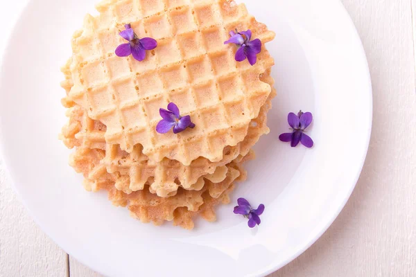 Cialde belghe su piatto bianco su sfondo di legno decorato fiore viola. Vista dall'alto . — Foto Stock