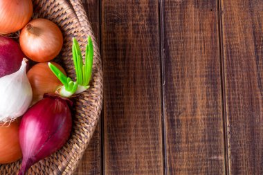 Farklı soğan sepeti ahşap arka plan üzerinde. Rustik tarzı. Uzay kopyalayın. Üstten Görünüm.