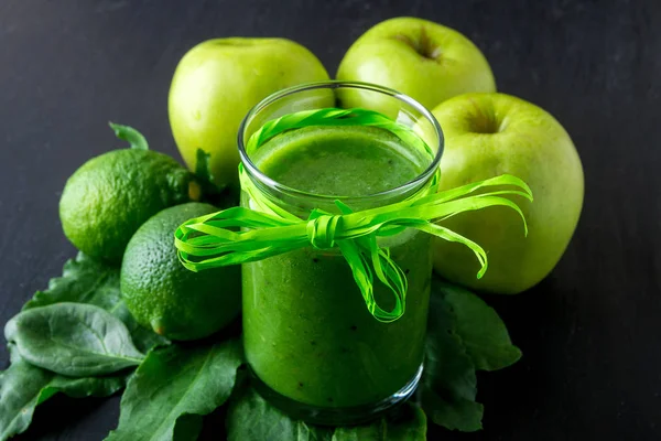 Frullato verde vicino a ingredienti per esso su sfondo di legno nero. Mela, lime, spinaci. Disintossicazione. Bevanda sana . — Foto Stock