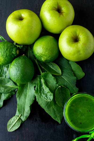 Batido verde cerca de los ingredientes para ello sobre fondo de madera negro. Manzana, lima, espinacas. Desintoxicación. Bebida saludable. Vista superior . —  Fotos de Stock