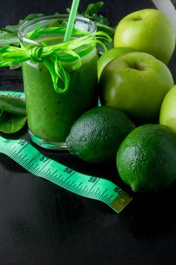 Yeşil smoothie santimetre ve siyah ahşap zemin üzerine bunun için malzemeler. Diyet. Detoks. Sağlıklı içecek.