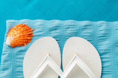 Beyaz flip flop yakınındaki seashell mavi zemin üzerine. Üstten Görünüm.