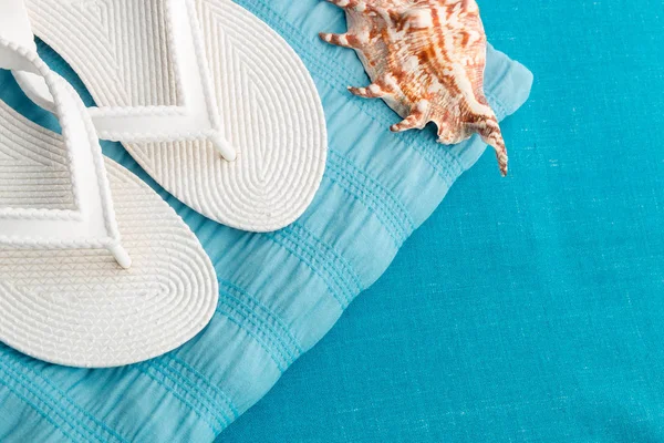 Beyaz flip flop yakınındaki seashell mavi zemin üzerine. Üstten Görünüm.