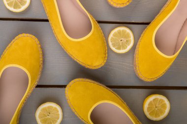 Sarı espadrilles ayakkabıları ahşap arka plandaki limon dilimlerinin yanında. Üst görünüm.