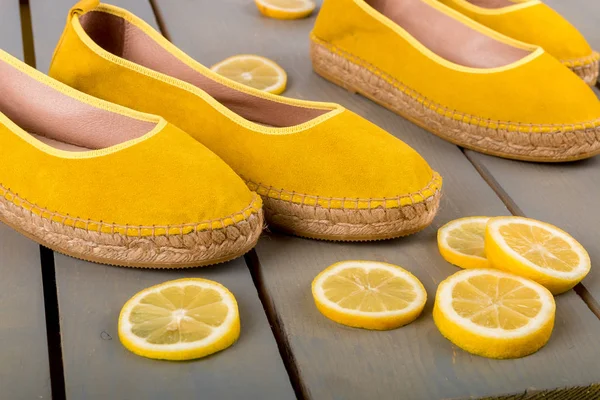 Žluté plátěné boty boty poblíž plátky citronu na dřevěné pozadí. Detailní záběr. — Stock fotografie