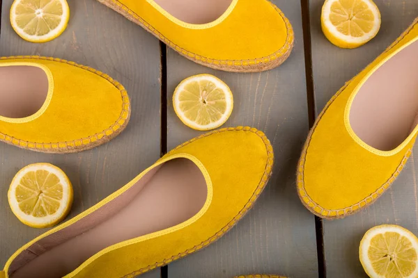Žluté espadrilles boty u plátků citronu na dřevěném pozadí. Horní pohled. — Stock fotografie