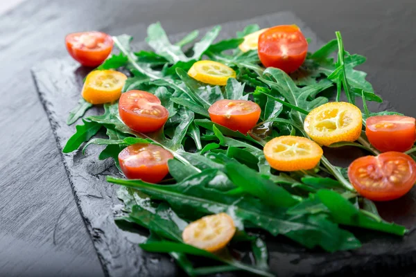 Vegetarischer Rucolasalat mit Kumquat und Tomatenkirsche auf Schieferteller. Gesunde Ernährung. Ernährung. — Stockfoto